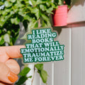 Transparent bookish sticker with the quote "i like reading books that will emotionally traumatize me forever". 