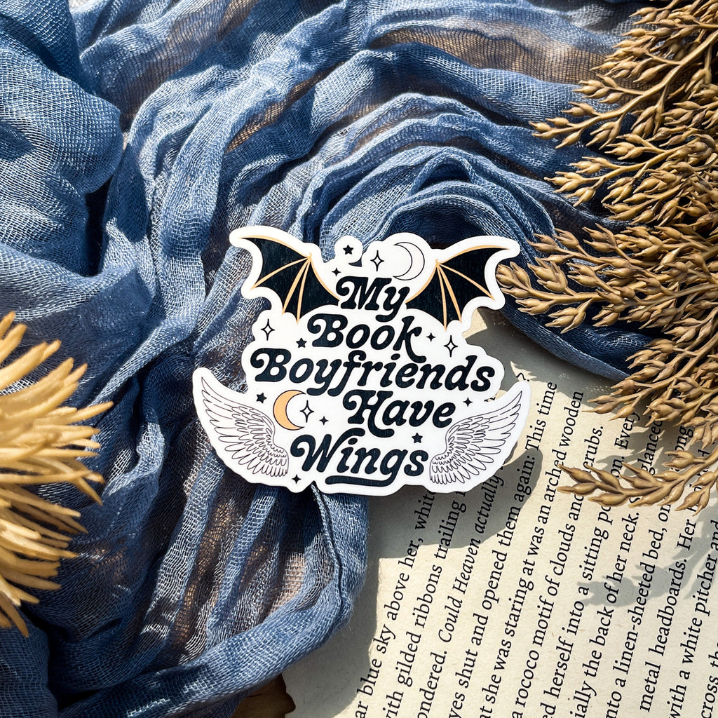 A sticker with a design that includes a bat, moon, and stars, with the text 'MY BOOK BOYFRIENDS HAVE WINGS'.