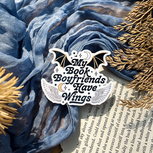 A sticker with a design that includes a bat, moon, and stars, with the text 'MY BOOK BOYFRIENDS HAVE WINGS'.