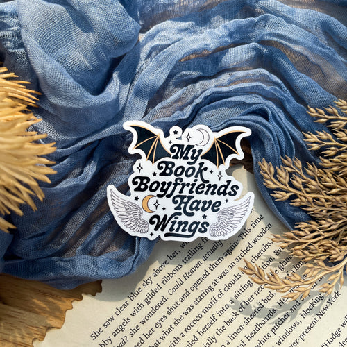 A sticker with a design that includes a bat, moon, and stars, with the text 'MY BOOK BOYFRIENDS HAVE WINGS'.