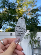 A hand holding a white marble acrylic motel keychain engraved with black sparkles and the text "when you are young they assume you know nothing"