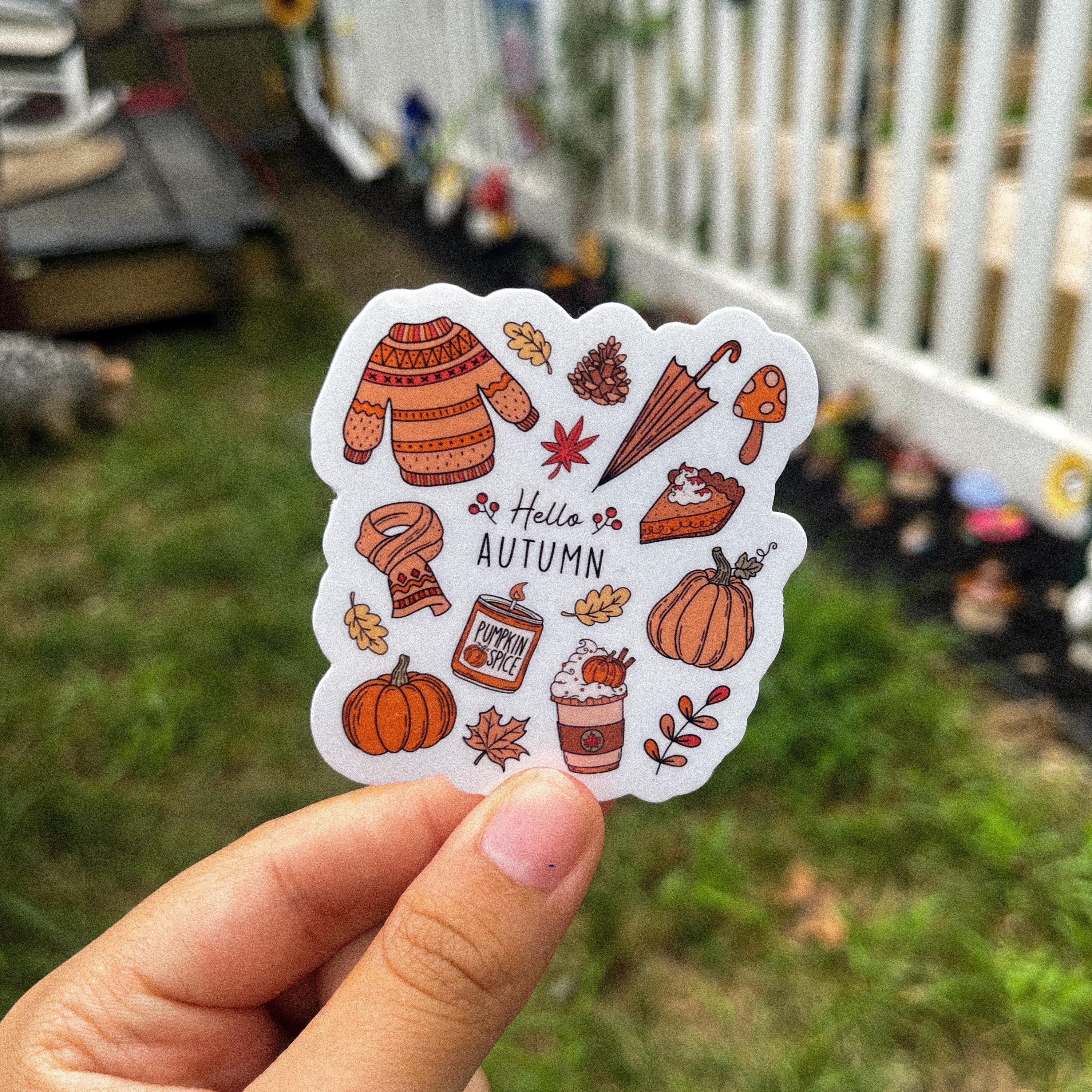 A sticker with a fall-themed design, including the text 'Hello Autumn' and various autumn-related illustrations such as pumpkins, leaves, and pumpkin spice sweets.