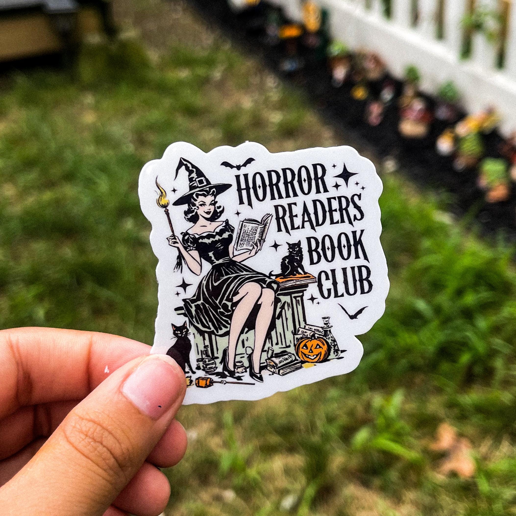Witch reading a book with black cats, with the text "horror readers book club."
