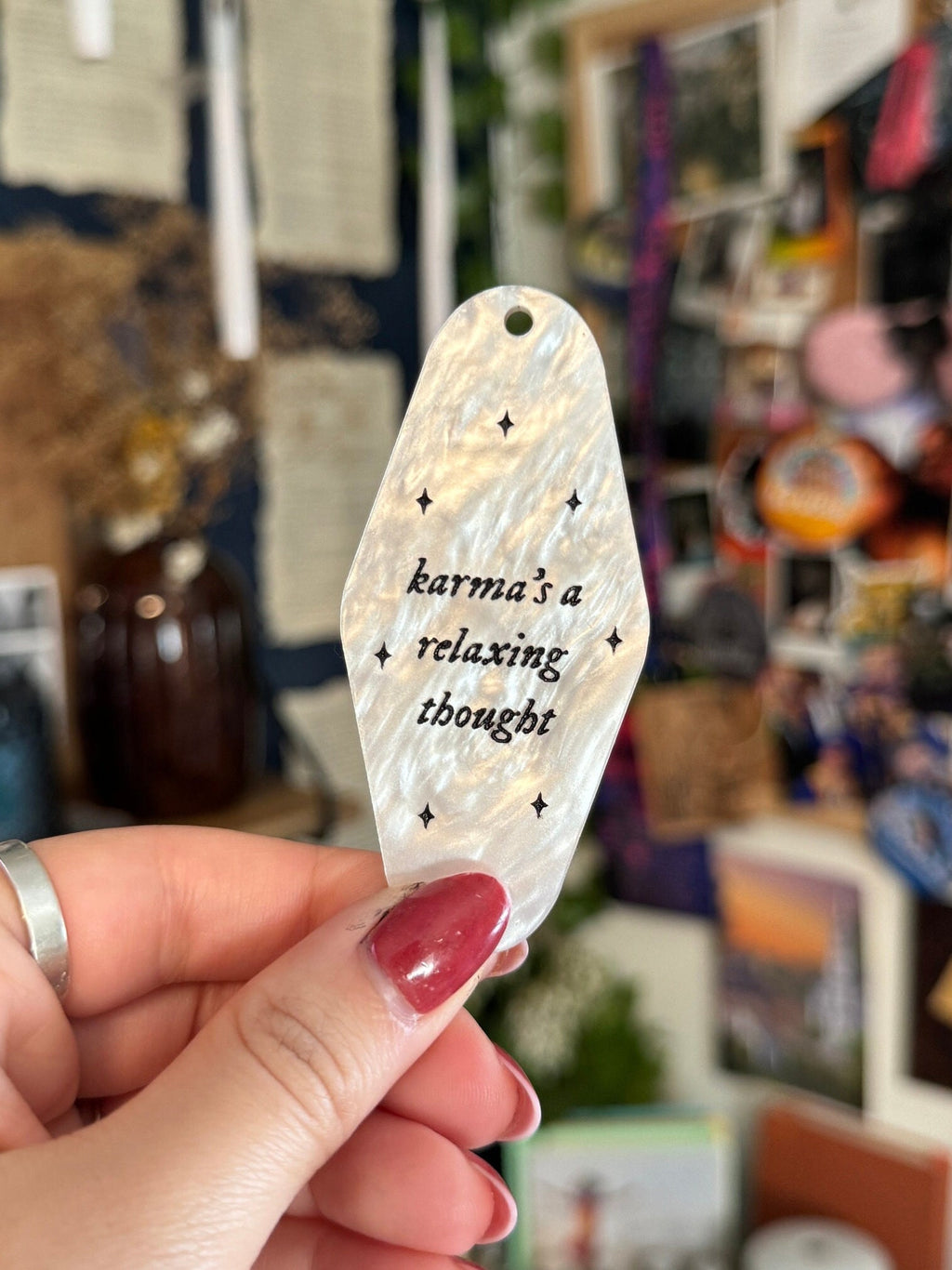 White marble acrylic motel keychain engraved with black sparkles and the lyrics "karma's a relaxing thought.'