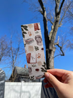 A bookmark with a light academic aesthetic design, featuring a mix of book-related imagery such as books, a camera, and decorative elements against a patterned background.