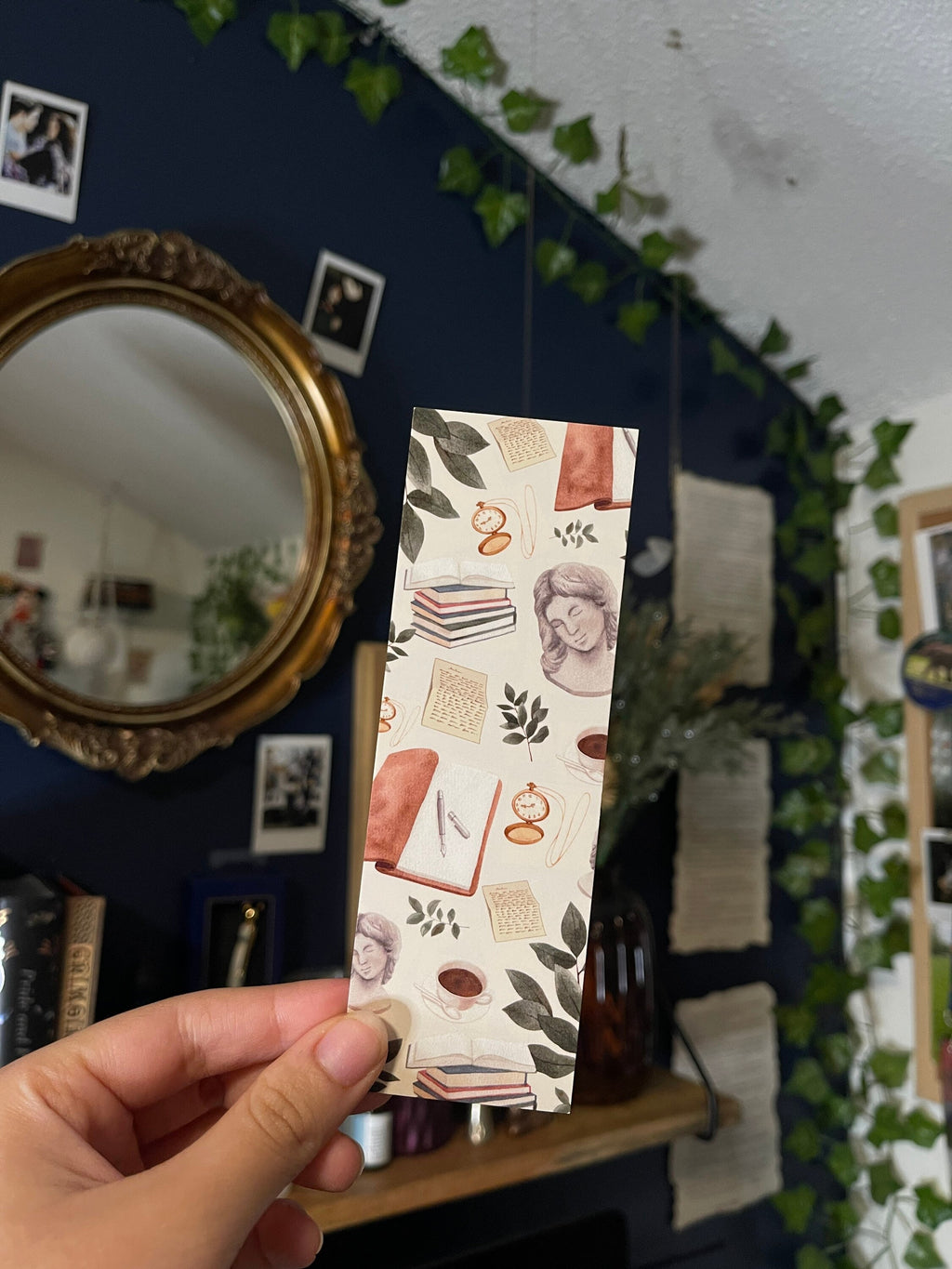 A bookmark with a light academic aesthetic design, featuring a mix of book-related imagery such as books, a camera, and decorative elements against a patterned background.
