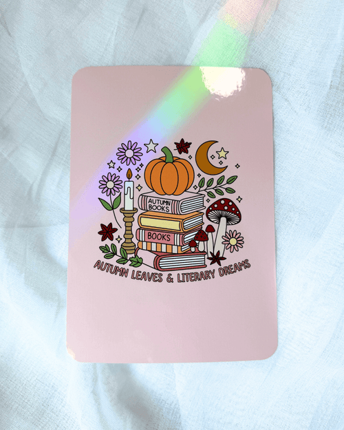 A kindle insert featuring an autumn-themed illustration of books, a pumpkin, mushrooms, stars, etc., and the text 'AUTUMN LEAVES & LITERARY DREAMS'. 