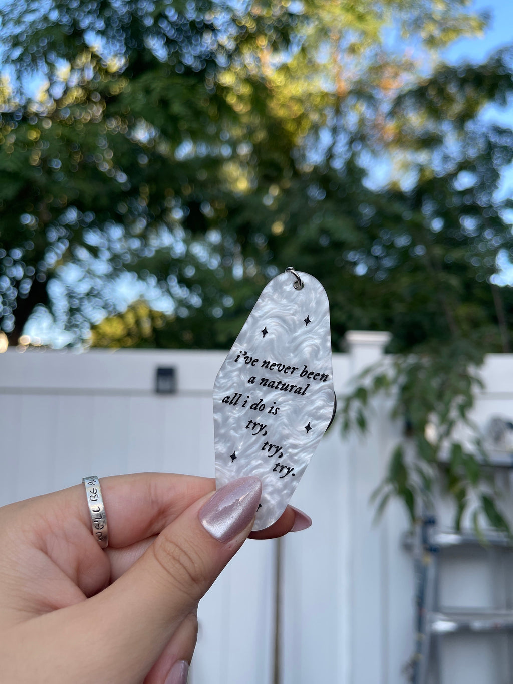 A white marble acrylic motel chain engraved with black sparkles and the text "i've never been a natural, all i do is try, try, try."