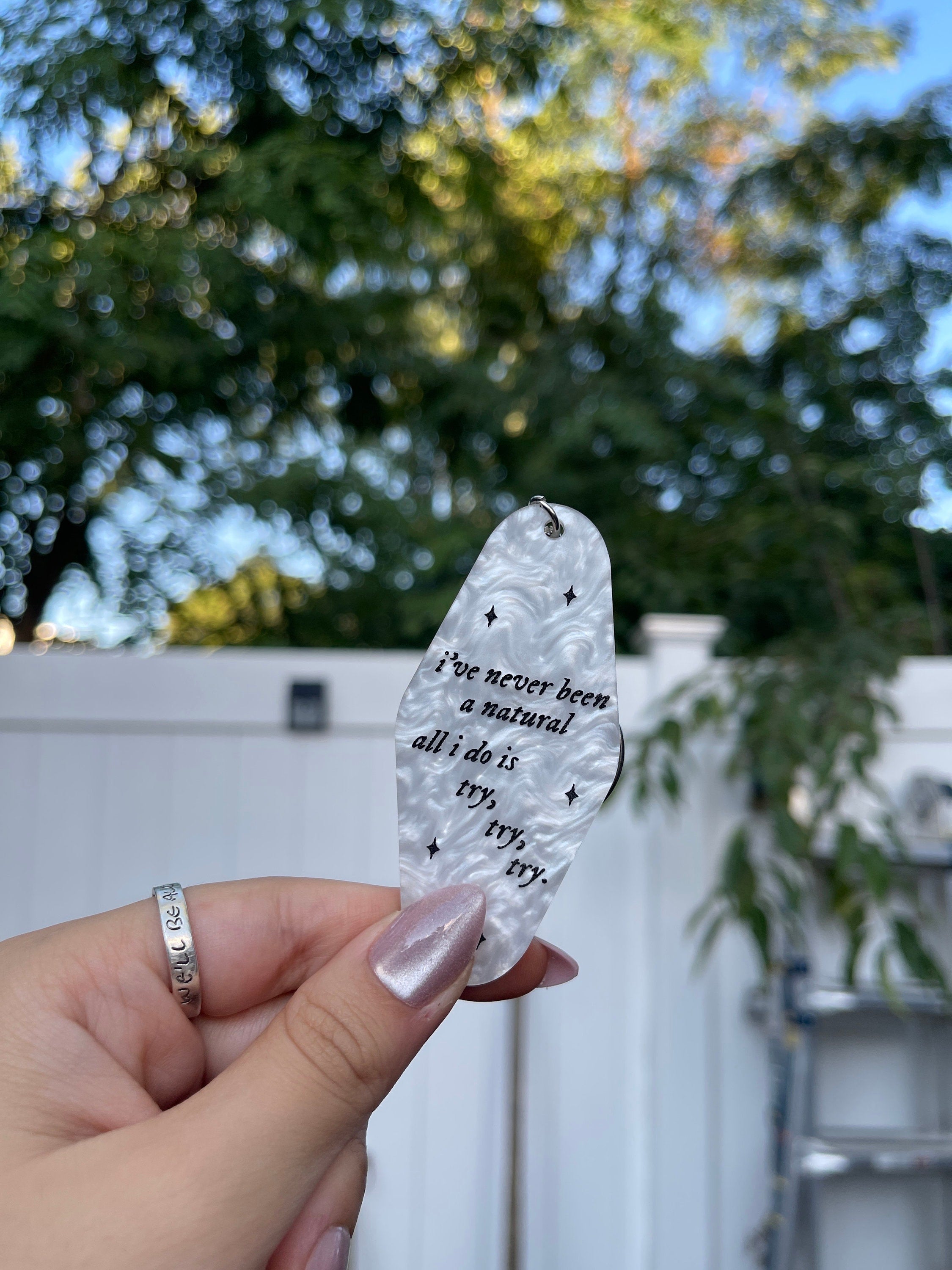 A white marble acrylic motel chain engraved with black sparkles and the text "i've never been a natural, all i do is try, try, try."