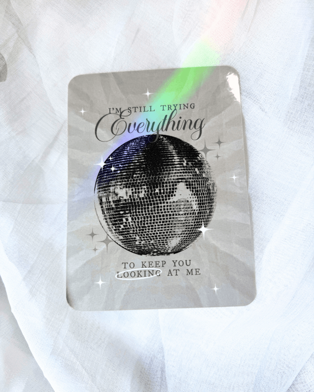 Grayish kindle insert with a large mirrorball and the quote "i'm still trying everything to keep you looking at me."