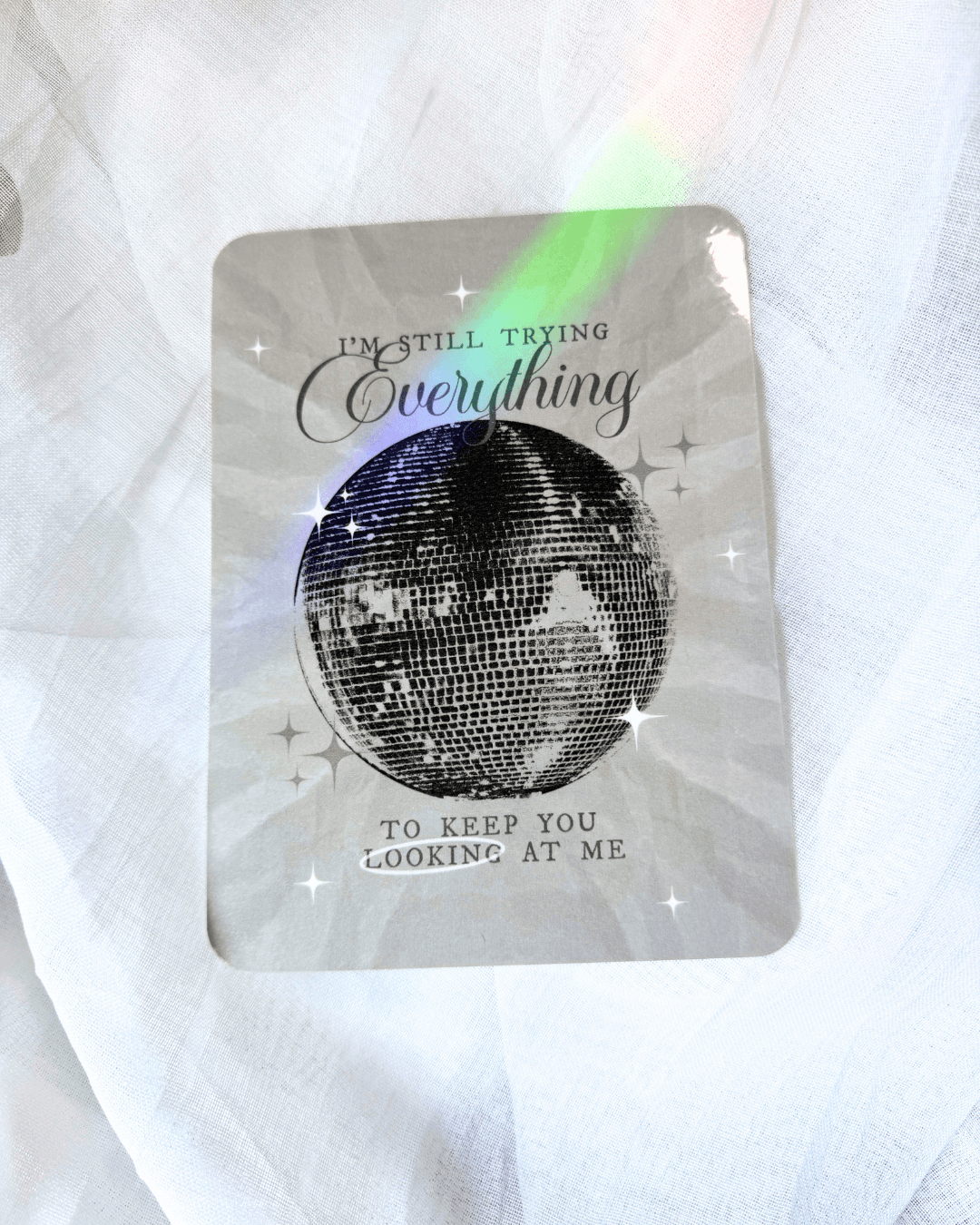 Grayish kindle insert with a large mirrorball and the quote "i'm still trying everything to keep you looking at me."