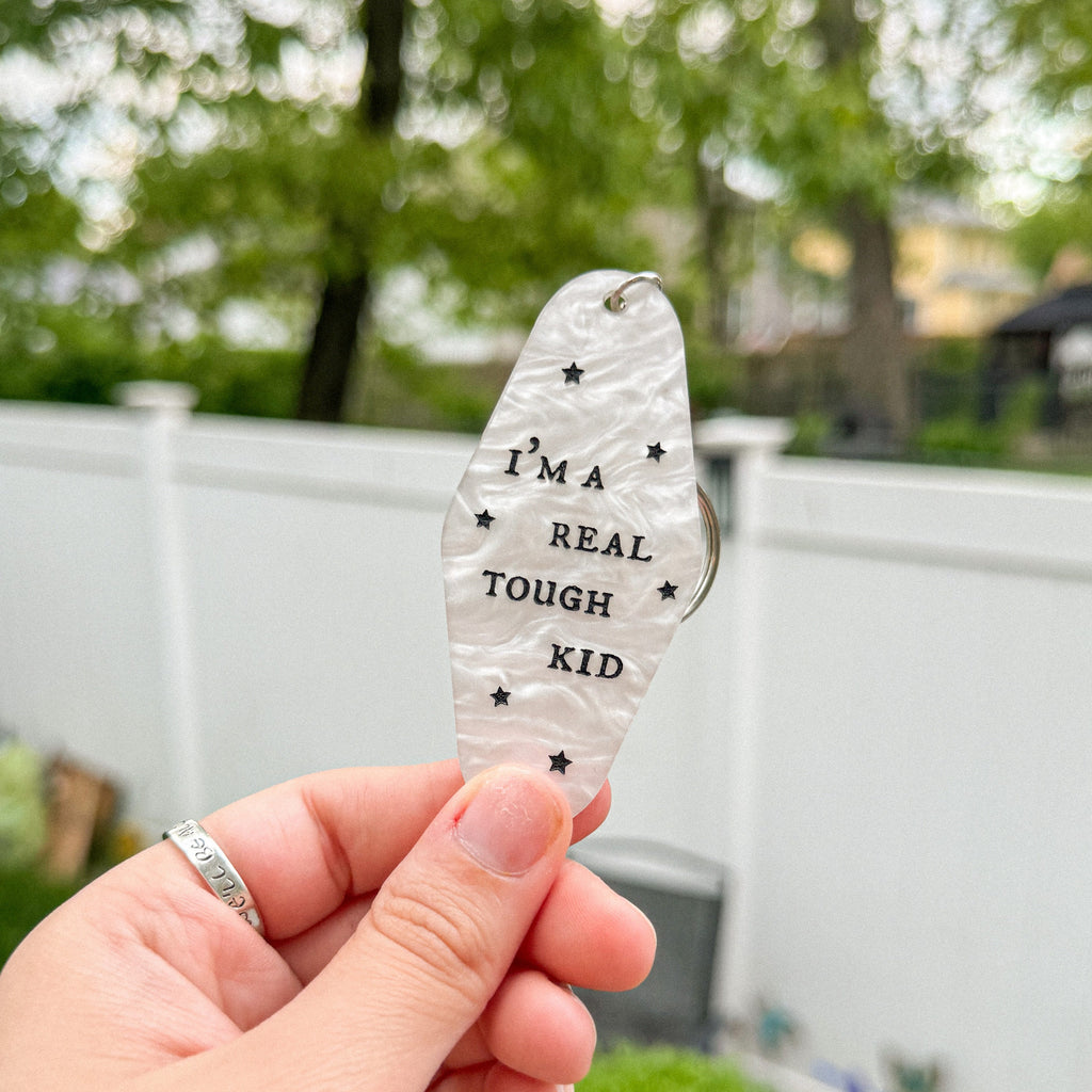 A white marble acrylic motel chain engraved with black stars and the text "I'm a real tough kid."