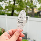 A white marble acrylic motel chain engraved with black stars and the text "I'm a real tough kid."