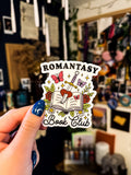 A transparent sticker with a book, butterfly, sword, and rose design, with the text 'Romantasy Book Club'.
