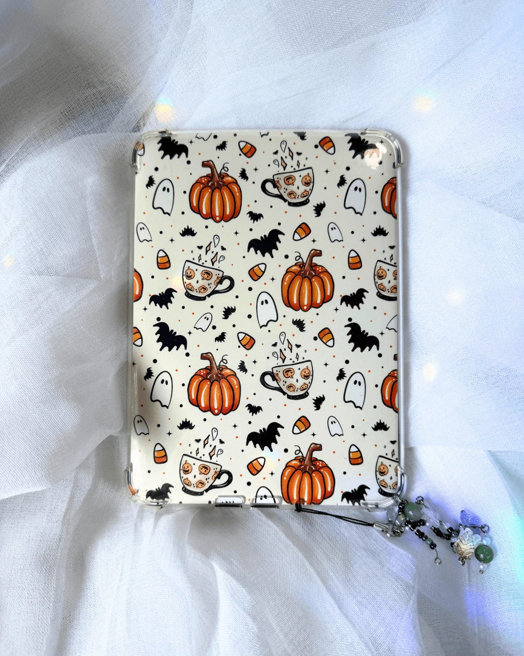 A kindle insert with a Halloween-themed pattern featuring orange pumpkins, black bats, white ghosts, and orange-and-white coffee cups.