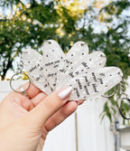 a hand holding 5 different taylor swift inspired motel keychains