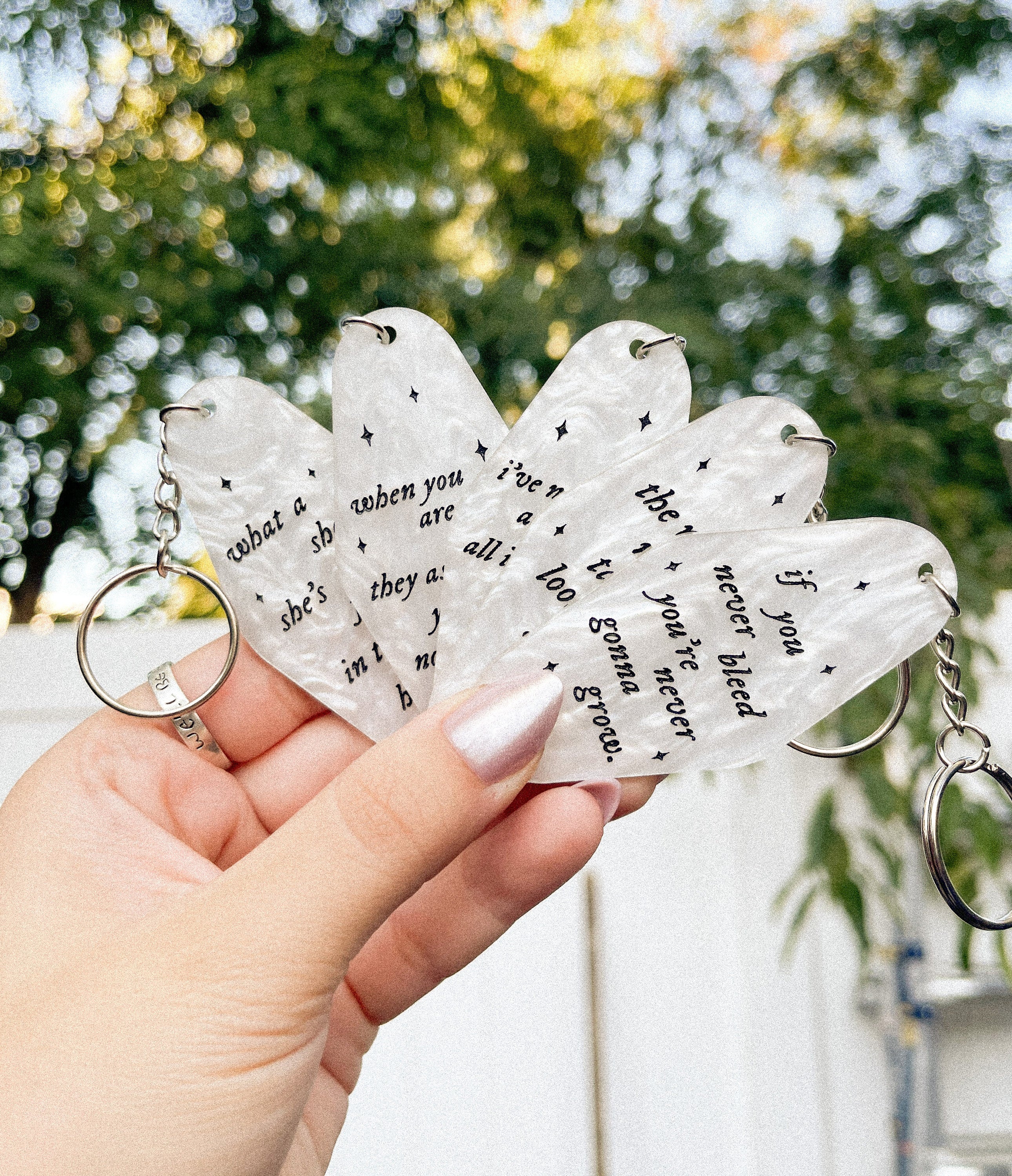 a hand holding 5 different taylor swift inspired motel keychains