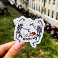 A sticker with a cartoon illustration of two skeletons dancing and the text 'IT'S THE SEASON TO BE SPOOKY'.