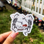 A sticker with a cartoon illustration of two skeletons dancing and the text 'IT'S THE SEASON TO BE SPOOKY'.