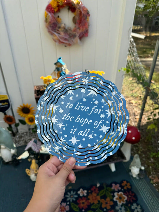 A circular blue wind spinner with white stars and text with the lyrics 'to live for the hope of it all' by taylor swift
