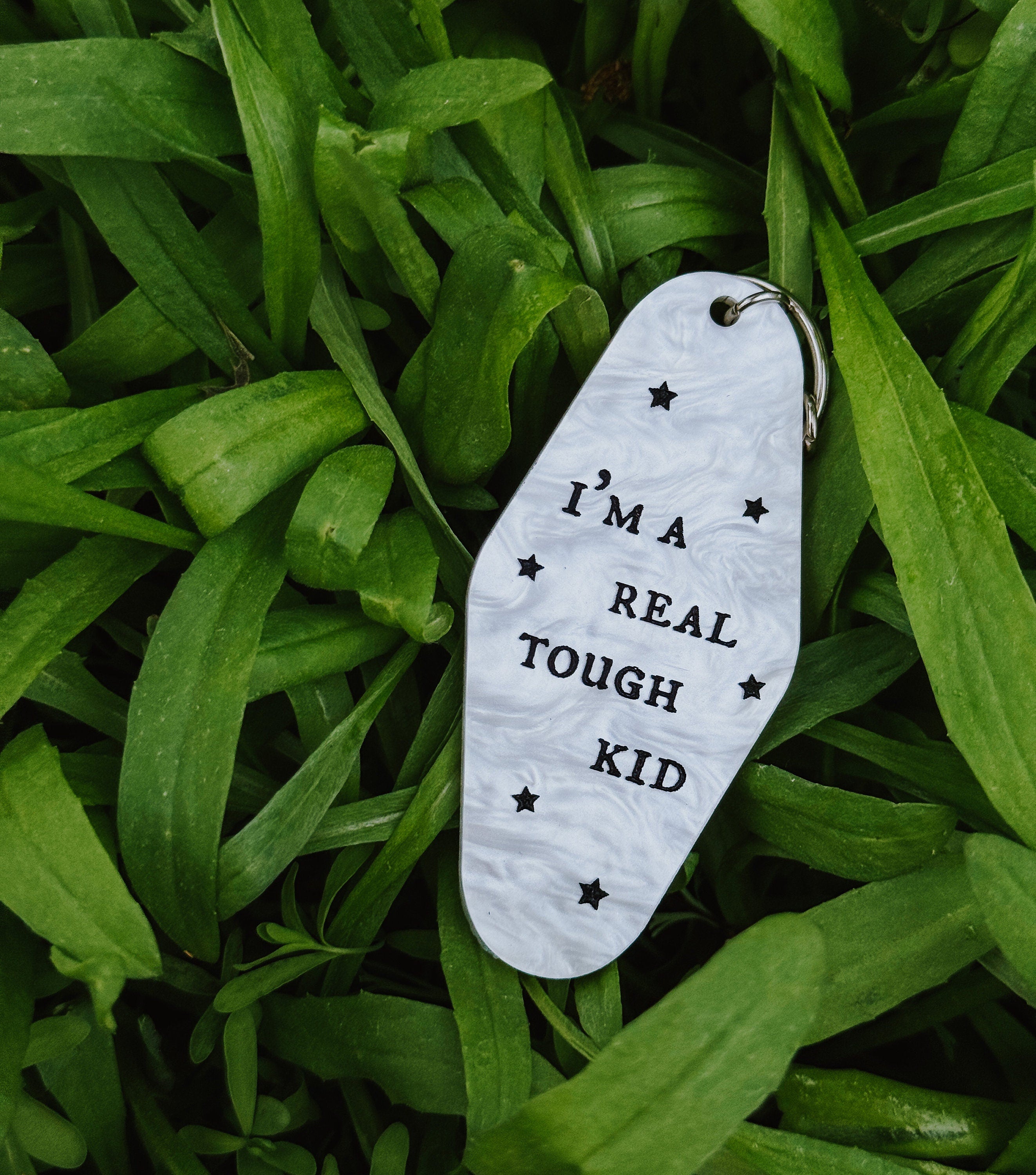 A white marble acrylic motel chain engraved with black stars and the text "I'm a real tough kid."