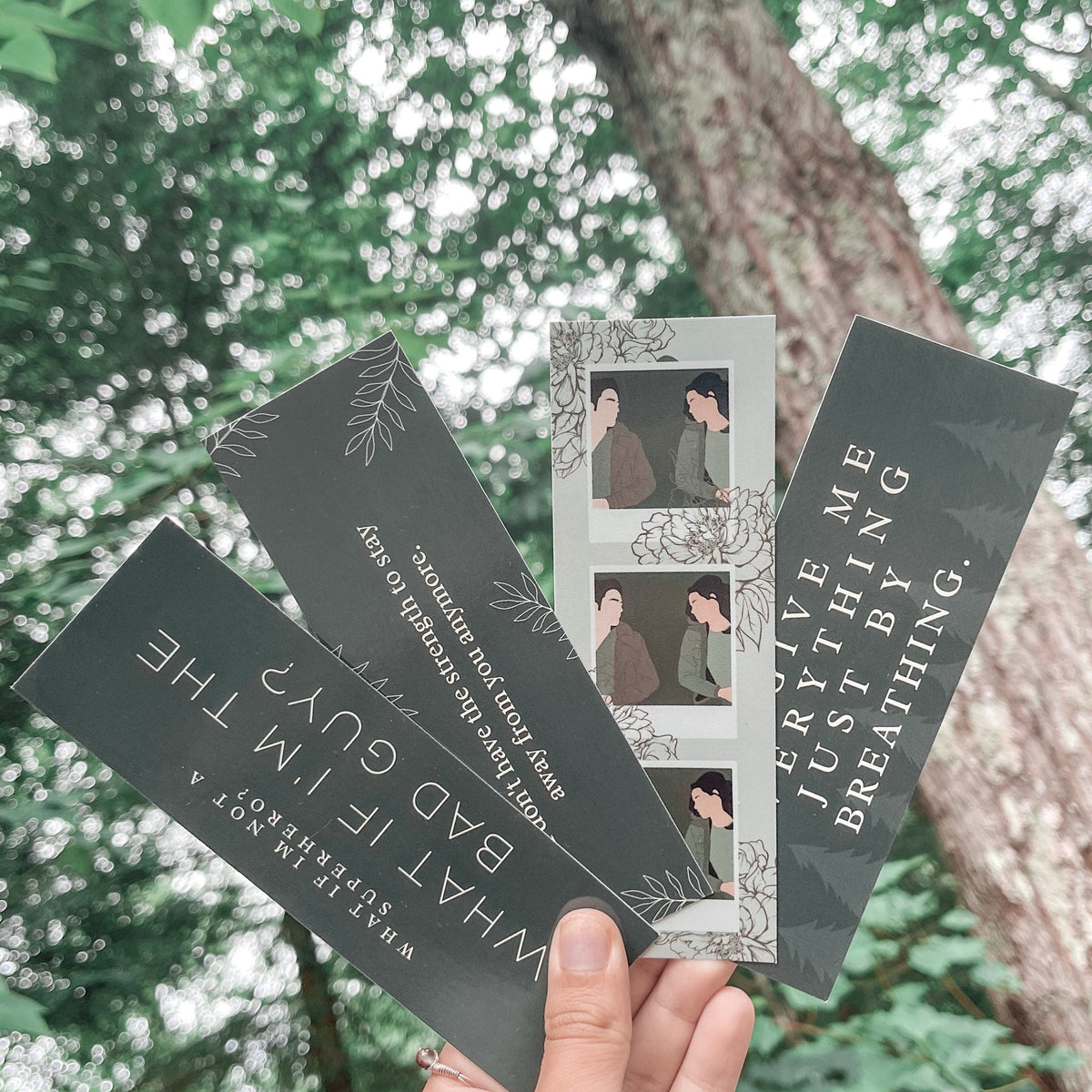 A collection of four bookmarks with Twilight-related quotes and imagery, held in a hand against a natural background.