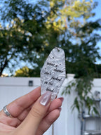 A hand holding a white marble acrylic motel keychain engraved with black sparkles and the text "what a shame she's fucked in the head"